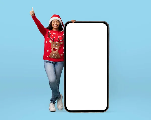 Noel Baba şapkalı mutlu kadın büyük akıllı telefonun yanında duruyor. — Stok fotoğraf