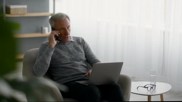 Trabajo independiente en jubilación. Hombre mayor usando teléfono celular y portátil en casa — Vídeos de Stock