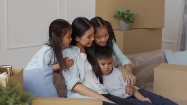 한국 아이들, 박스 안의 소파에 앉아 엄마를 껴안고 있는 모습 — 비디오