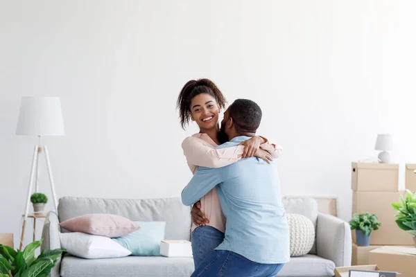 Emocionado joven pareja negra feliz celebrando la compra de una nueva casa, marido levantando esposa, en el día de mudanza — Foto de Stock