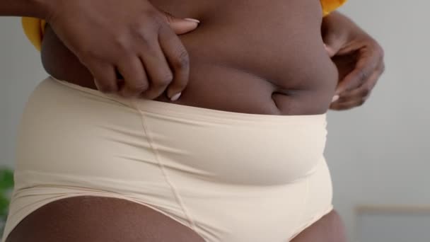Sobrepeso. preto plus size mulher em roupa interior tocando gordura em sua barriga — Vídeo de Stock