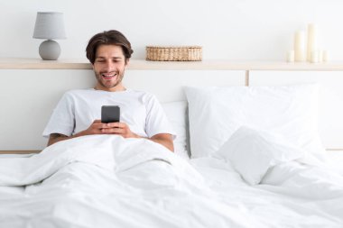 Milenyum Avrupalı neşeli, sakallı, telefonda oynaşan akıllı telefondan internette sörf yapan adam.