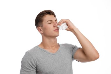 Hüzünlü genç beyaz yakışıklı adam peçeteyi burnuna bastırıyor ve kanaması ya da burnu akıyor.