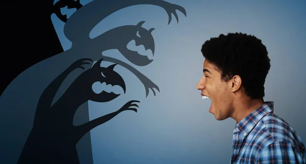 Vista lateral de chico adolescente negro gritando a siluetas monstruo miedo, luchando contra sus miedos internos en el fondo oscuro, collage — Foto de Stock