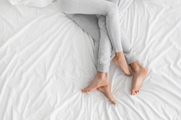 Pernas de europeu millennial cara e mulher mentira na cama branca no quarto — Fotografia de Stock