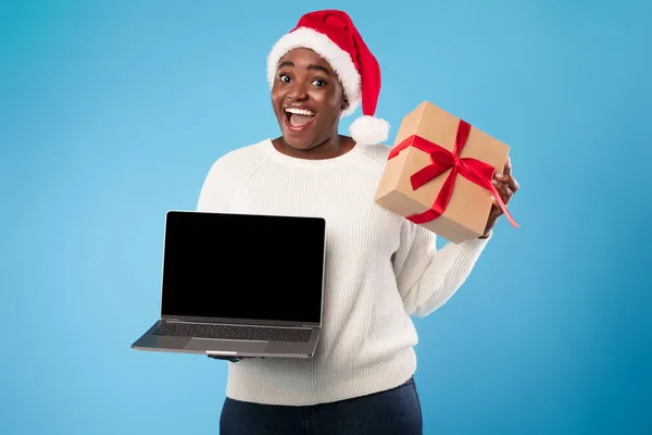 Black Lady Showing Laptop Screen Holding Christmas Present, Blue Background — Stock Photo, Image