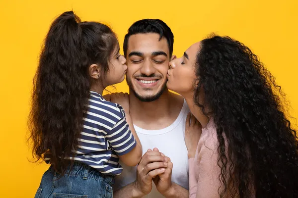 Esposa e filha beijando feliz jovem árabe homem em ambas as bochechas, close-up — Fotografia de Stock