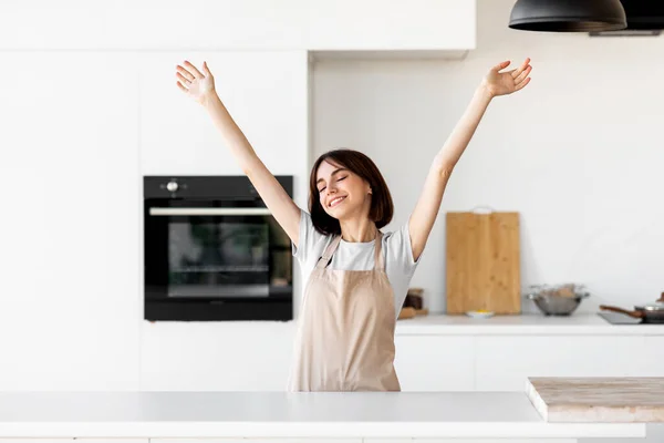 Ontspannen jongedame het verhogen van de handen en het gevoel opgewonden koken alleen in de moderne keuken interieur, plezier hebben — Stockfoto