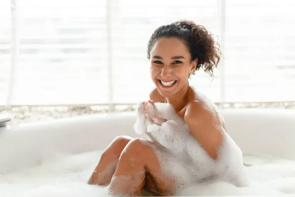 Portrait de femme millénaire souriante recouverte de mousse assise dans un bain à bulles chaud à la maison, espace de copie — Photo