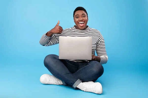 Mujer negra con sobrepeso usando pulgares de gestos de computadora portátil sobre fondo azul — Foto de Stock