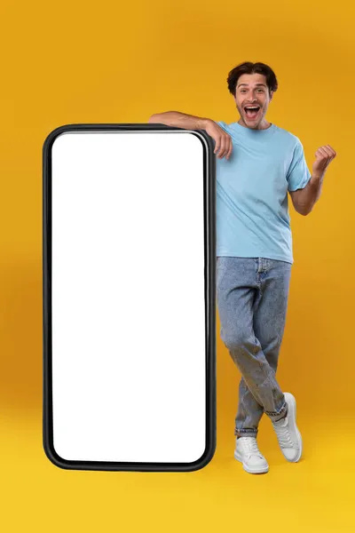 Возбужденный парень, опирающийся на пустой экран смартфона и жестикулирующий "да" — стоковое фото