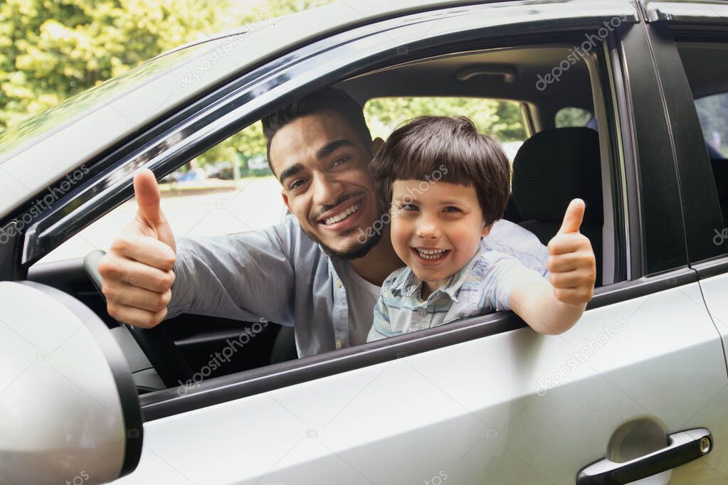 Happy Arab Father And Son Sitting In Car And Showing Thumbs Up