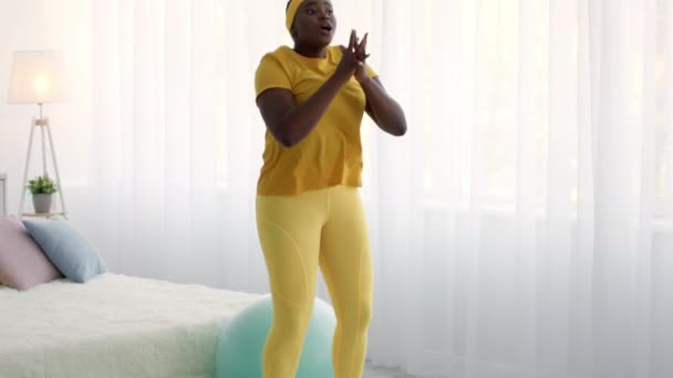 Das häusliche Training. Übergewichtige Afroamerikanerin macht Kniebeugen-Übungen zu Hause — Stockvideo