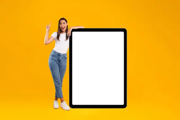 Femme pointant vers le haut penché sur grand écran de tablette vide blanc — Photo
