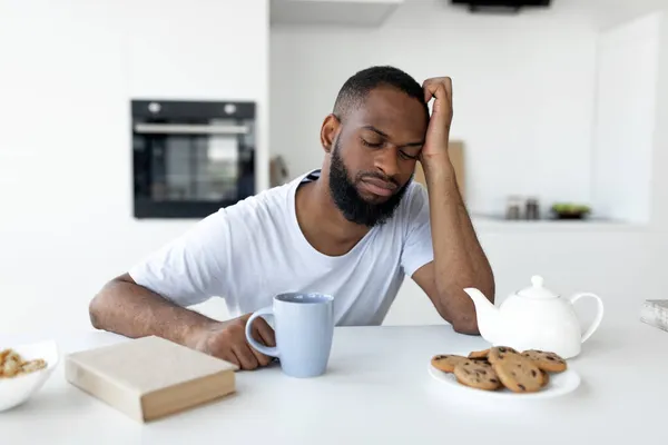 Zwarte man lijdt aan slapeloosheid zittend aan het bureau — Stockfoto