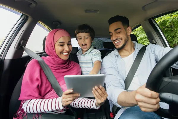 車の中で座ってデジタルタブレットを使用して息子と幸せなイスラム教徒の家族 — ストック写真