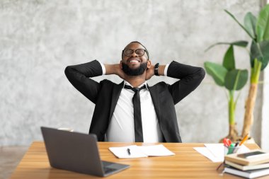 Afro-Amerikalı adam arkasını yaslıyor.