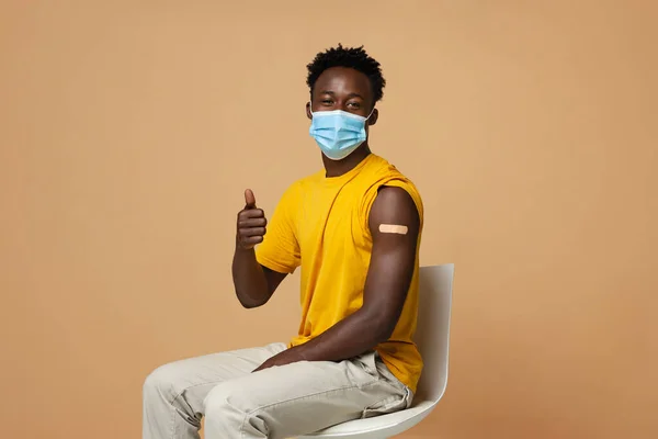 Vaccinationsreklam. Vaccinerad svart kille med gips på armen visar tummen upp — Stockfoto