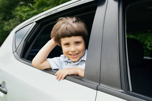 Arabayla gezerken pencereden dışarı bakan neşeli küçük çocuk. — Stok fotoğraf