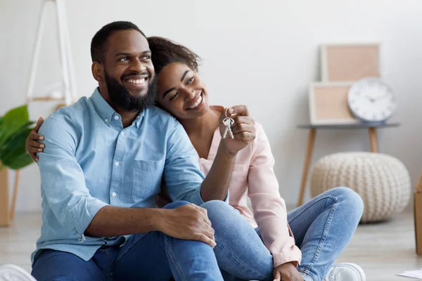 Glad tusenårig afrikansk amerikansk man och hustru flyttar till ny lägenhet, sitter bland lådor — Stockfoto