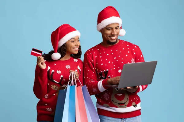 Laptop kullanan, yeni yıl hediyeleri alan mutlu siyah alışverişkolikler. — Stok fotoğraf