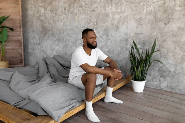 Homem negro sentado na cama e pensando — Fotografia de Stock