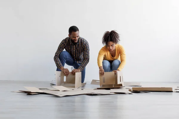 Jovem família negra empilhar caixas de papelão e se preparar para se mudar para a nova casa. Renovação, realocação e compra de nova casa — Fotografia de Stock