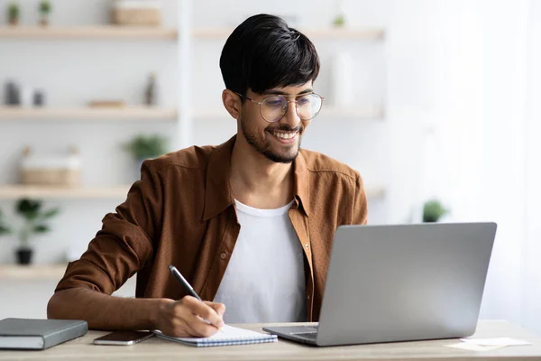 Schöner arabischer Typ, der im Internet surft und Notizen macht — Stockfoto