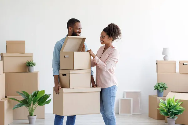 Lachen knappe jonge zwarte paar pak dozen van spullen in nieuw appartement, genieten van verhuizen — Stockfoto