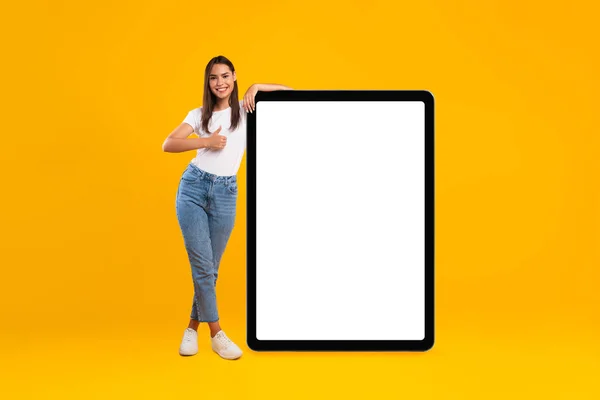 Donna felice mostrando schermo tablet vuoto bianco e pollice in su — Foto Stock