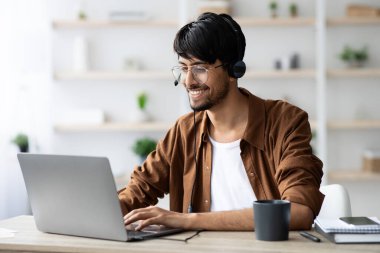 Webinar 'a katılan mutlu Hintli adam, dizüstü bilgisayarda klavye kullanıyor.