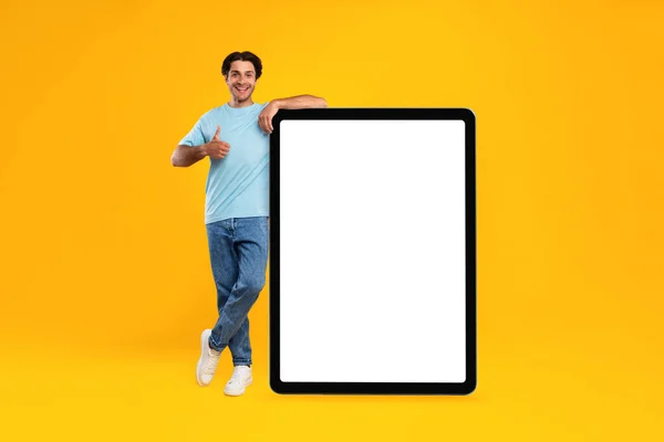 Счастливый человек показывает белый экран пустой столешницы и поднимает большой палец вверх — стоковое фото