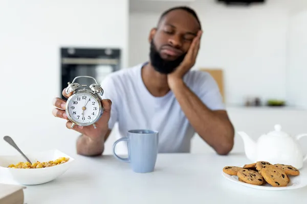 Zwarte man lijdt aan slapeloosheid bedrijf toont wekker — Stockfoto