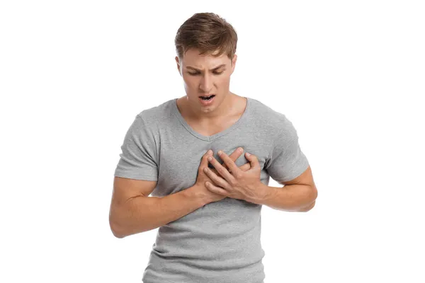 Despaired sad young european handsome guy presses his hands to sore spot and suffers from pain in chest — Stock Photo, Image
