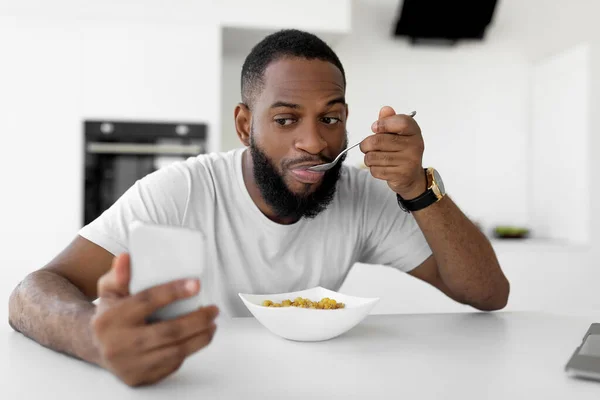 Negro hombre corriendo a trabajar comer cereal en casa — Foto de Stock