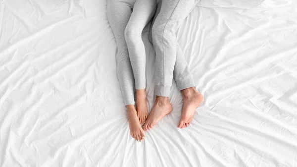 Pernas de branco europeu marido e mulher estão juntos na cama branca no quarto, vista superior — Fotografia de Stock