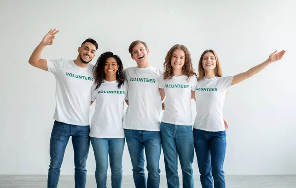 Jótékonysági szervezet. Fiatal multiracionális önkéntesek csoportja, akik átölelik a fényfalat, munkára készen — Stock Fotó