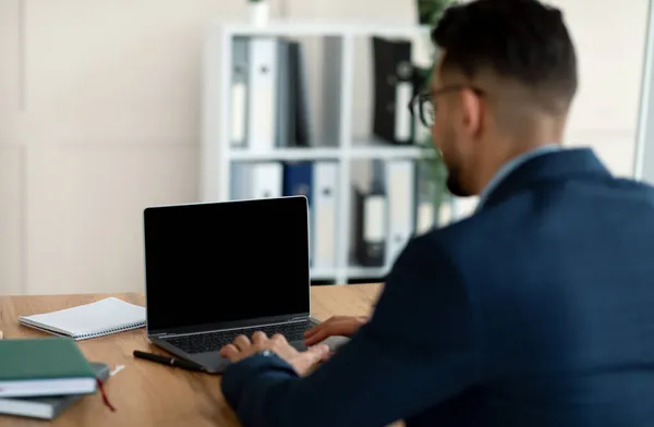 Unbekannter arabischer Unternehmer arbeitet an Laptop-PC mit leerem Bildschirm im Büro, Attrappe für Website-Design — Stockfoto