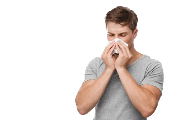 Olycklig tusenårig europeisk attraktiv man blåser näsan i servett och lider av rinnande näsa — Stockfoto
