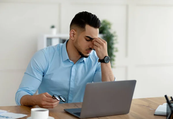 Millenniumi arab vállalkozó, akinek fáradt irritált szemét, túlterhelt laptop, kimerült az online munka az irodában — Stock Fotó