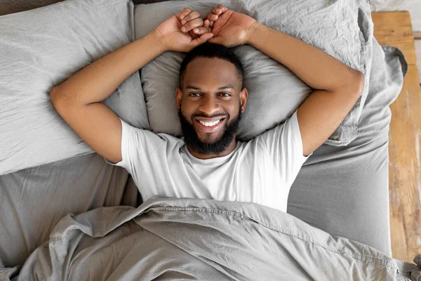 아프리카 계 미국인 청년이 깨어난 후 침대에 누워 있다 — 스톡 사진