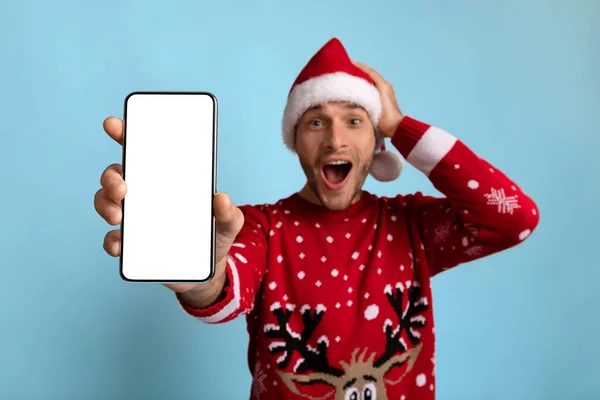 Increíble oferta. Chico emocionado en Santa Sombrero Demostración de Smartphone con pantalla en blanco — Foto de Stock