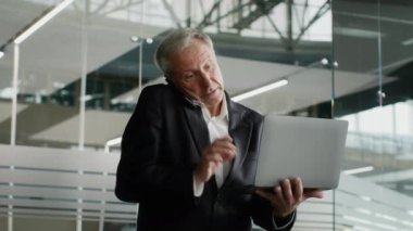 Ofiste dizüstü bilgisayarla konuşan orta yaşlı bir işadamı.