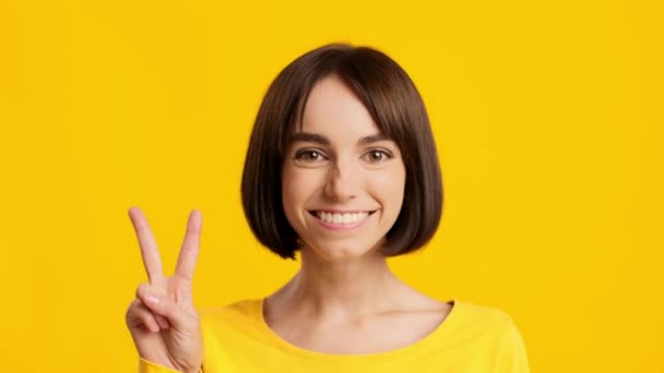 Happy Woman Gesturing V-Sign Posing Σε κίτρινο φόντο στούντιο — Αρχείο Βίντεο
