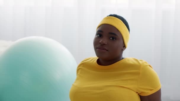 Zdenerwowany czarny nadwaga kobieta noszenie żółty Fitness Opaska smutno patrząc w aparat — Wideo stockowe