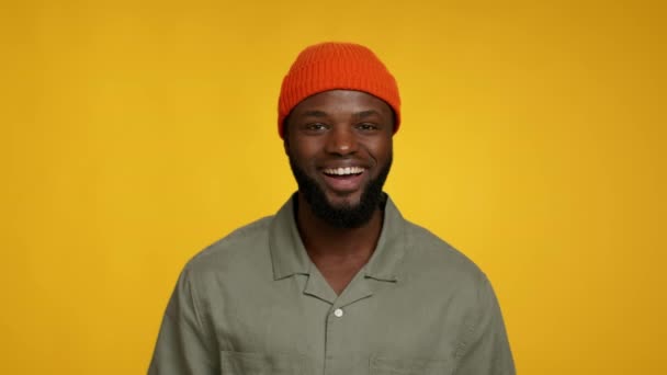 Goede Mood. zwarte man in oranje hoed kijken naar camera en glimlachen — Stockvideo