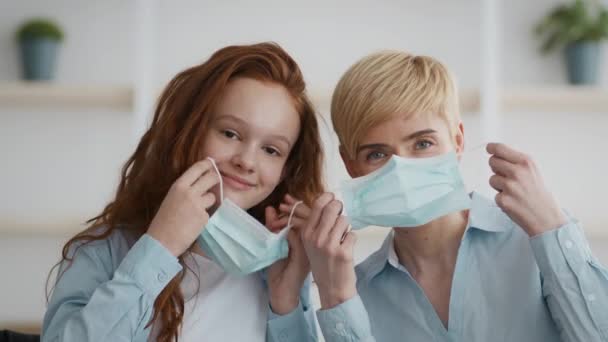 Prevención de brotes de virus. Linda niña y su madre de mediana edad poniéndose máscaras médicas protectoras — Vídeo de stock