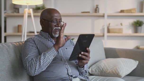 Comunicazione a distanza. Afroamericani nonno video chat con la famiglia, agitando mano al tablet digitale a casa — Video Stock