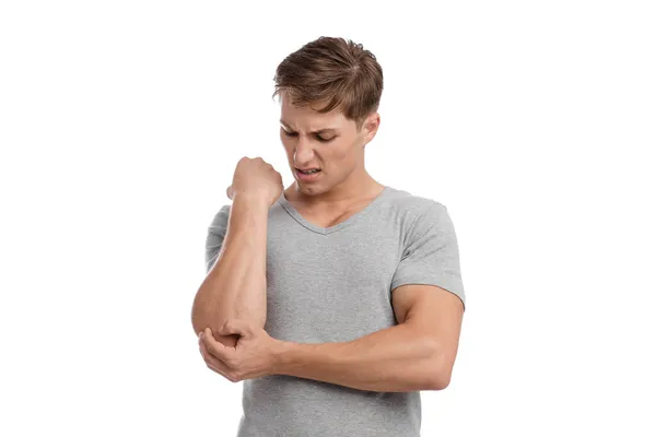 Desesperado joven europeo guapo chico presiona su mano para dolor de mancha y sufre de dolor en el codo — Foto de Stock