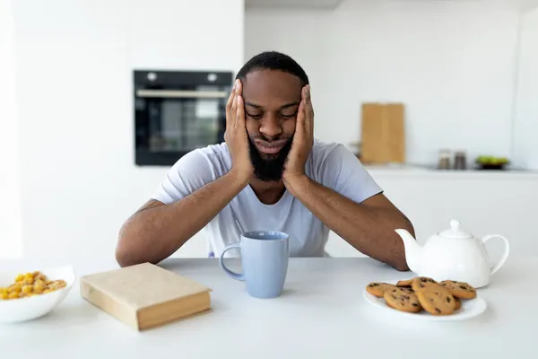 Zwarte man lijdt aan slapeloosheid zittend aan het bureau — Stockfoto